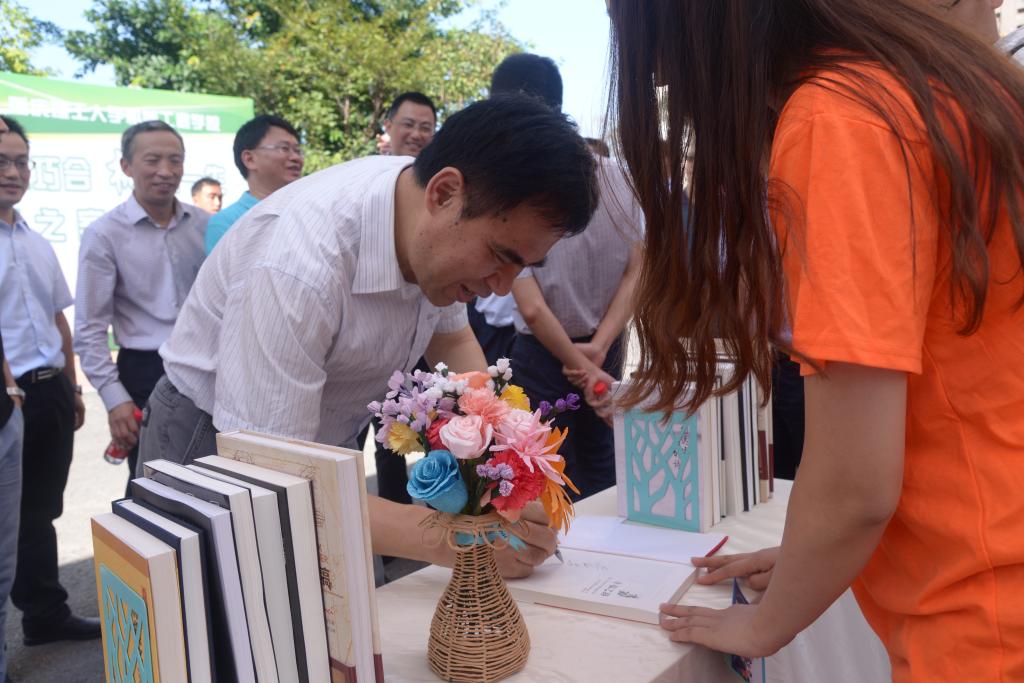 校党委书记李志雄在迎新现场为新生赠书题字