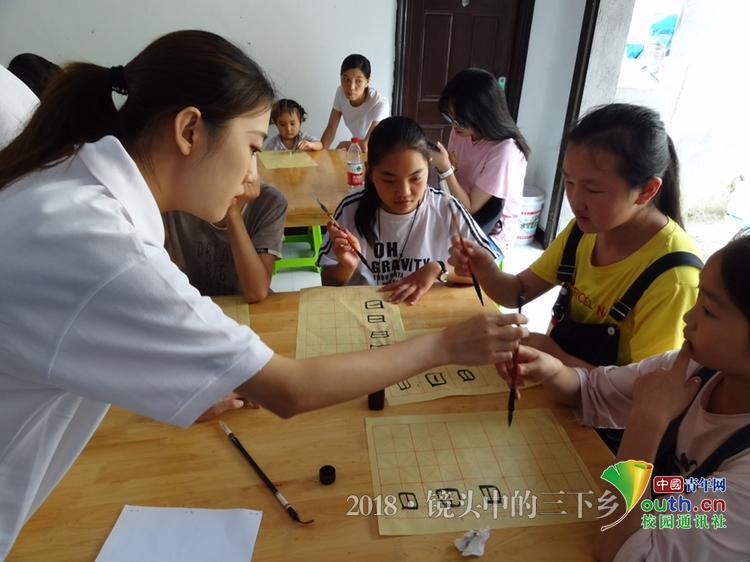 志愿者纠正小朋友的握笔姿势 中国青年网通讯员 况镇成 摄